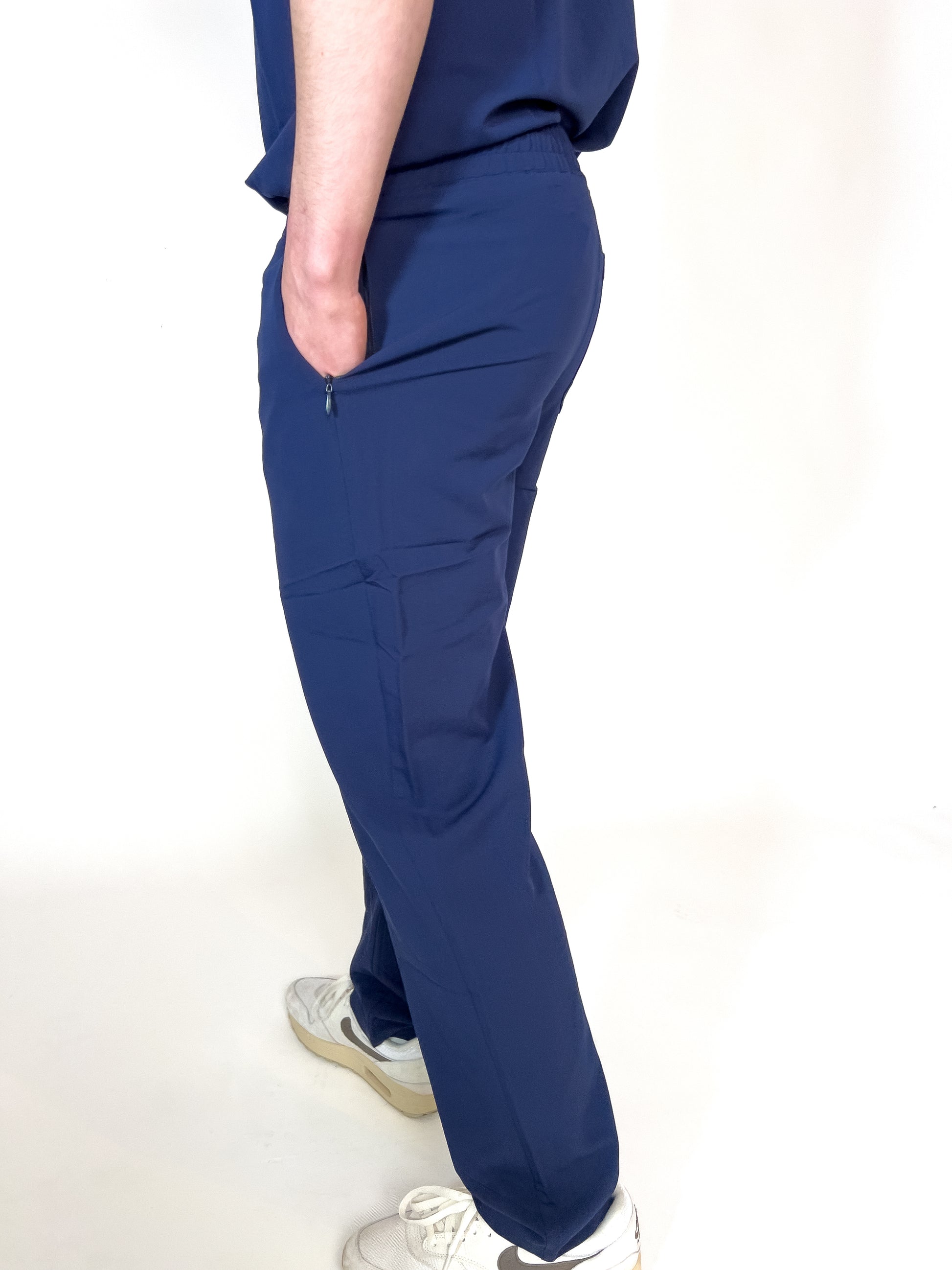 Healthcare worker with hand in the zippered hip pocket of blue PAX scrub bottoms.