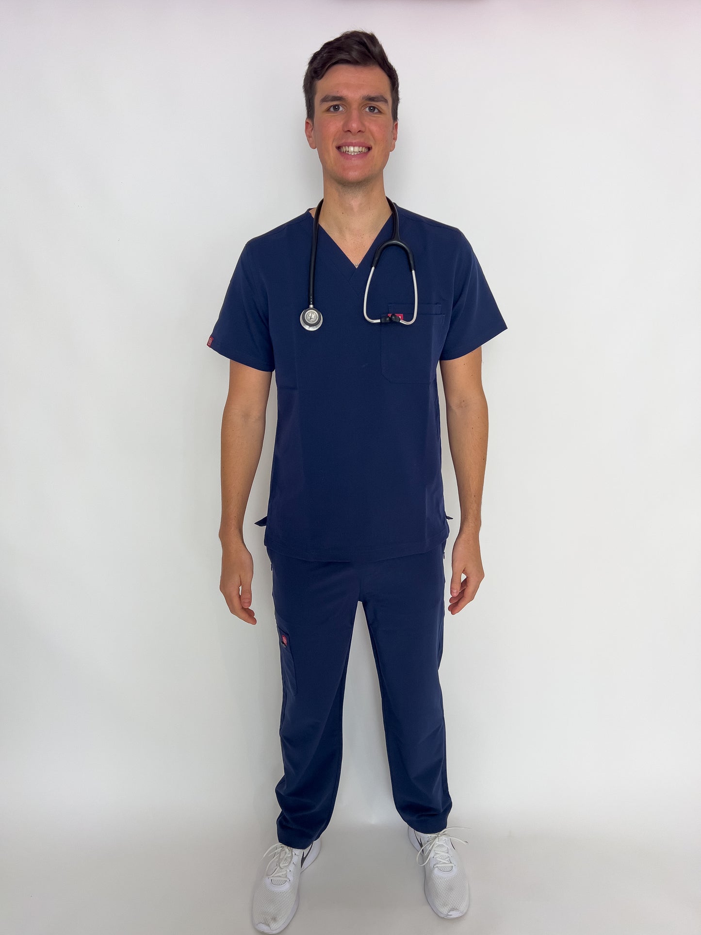Front view of a doctor with a stethoscope in a fitted royal blue PAX scrub set.