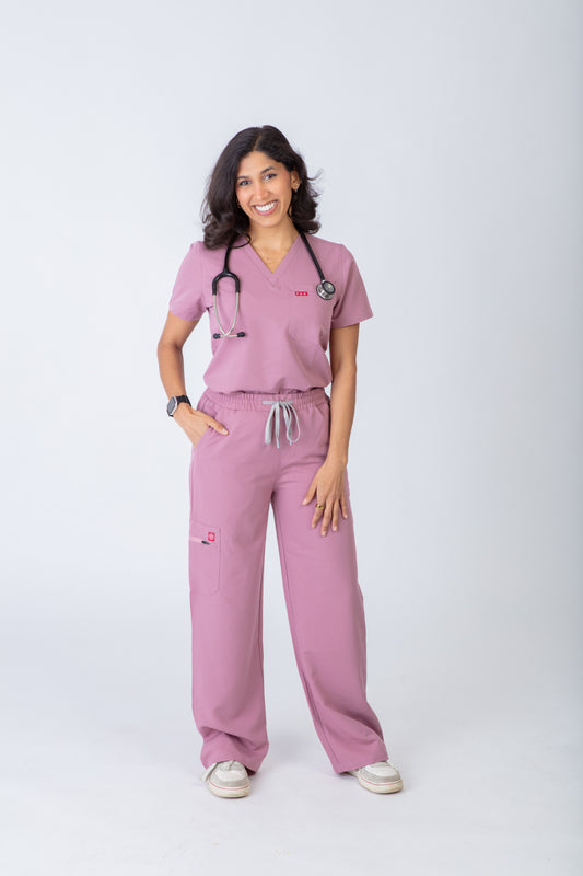Person wearing pink medical scrubs with a stethoscope on a white background