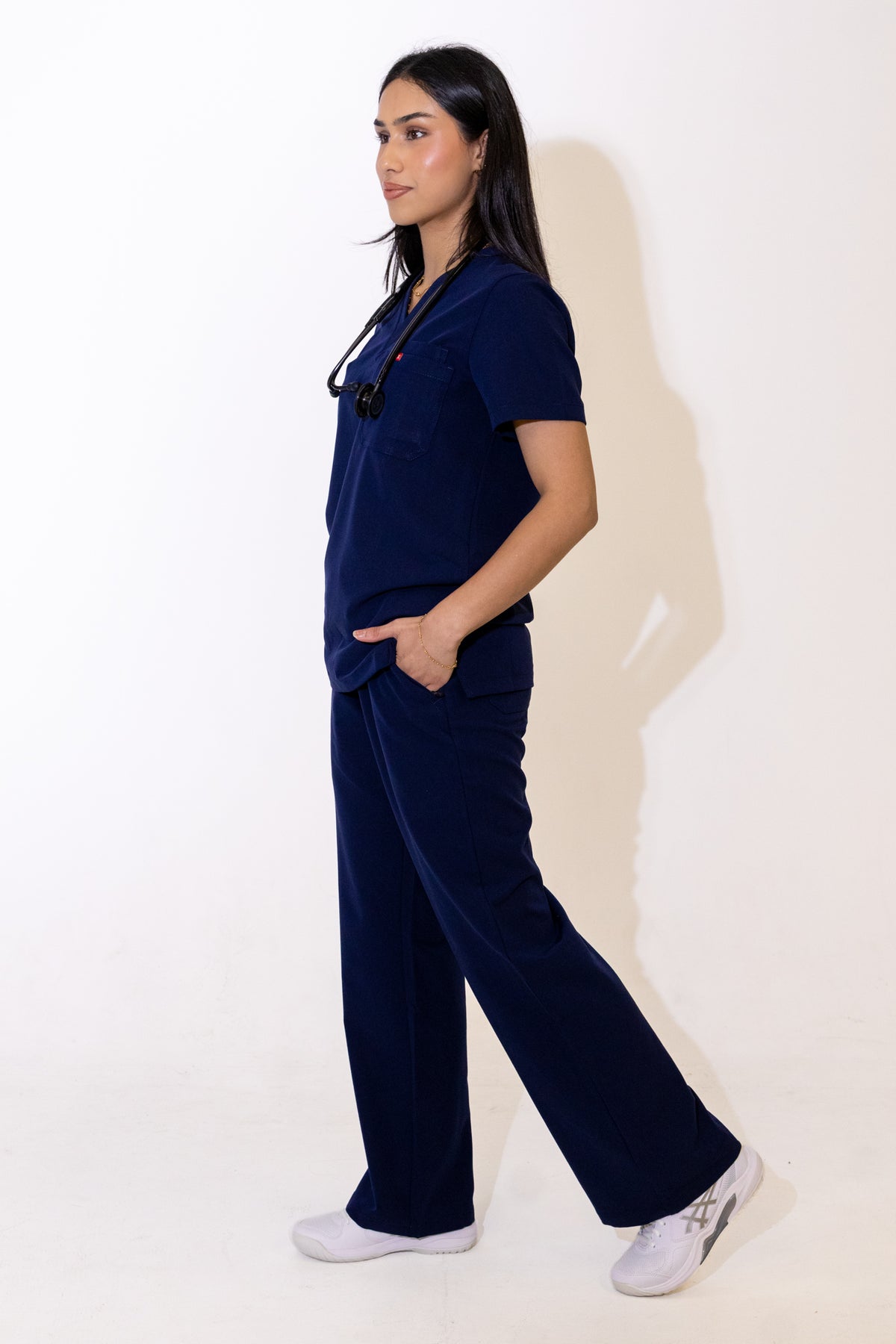 PAX Core Luma women's navy wide-leg scrub trousers, side view in movement