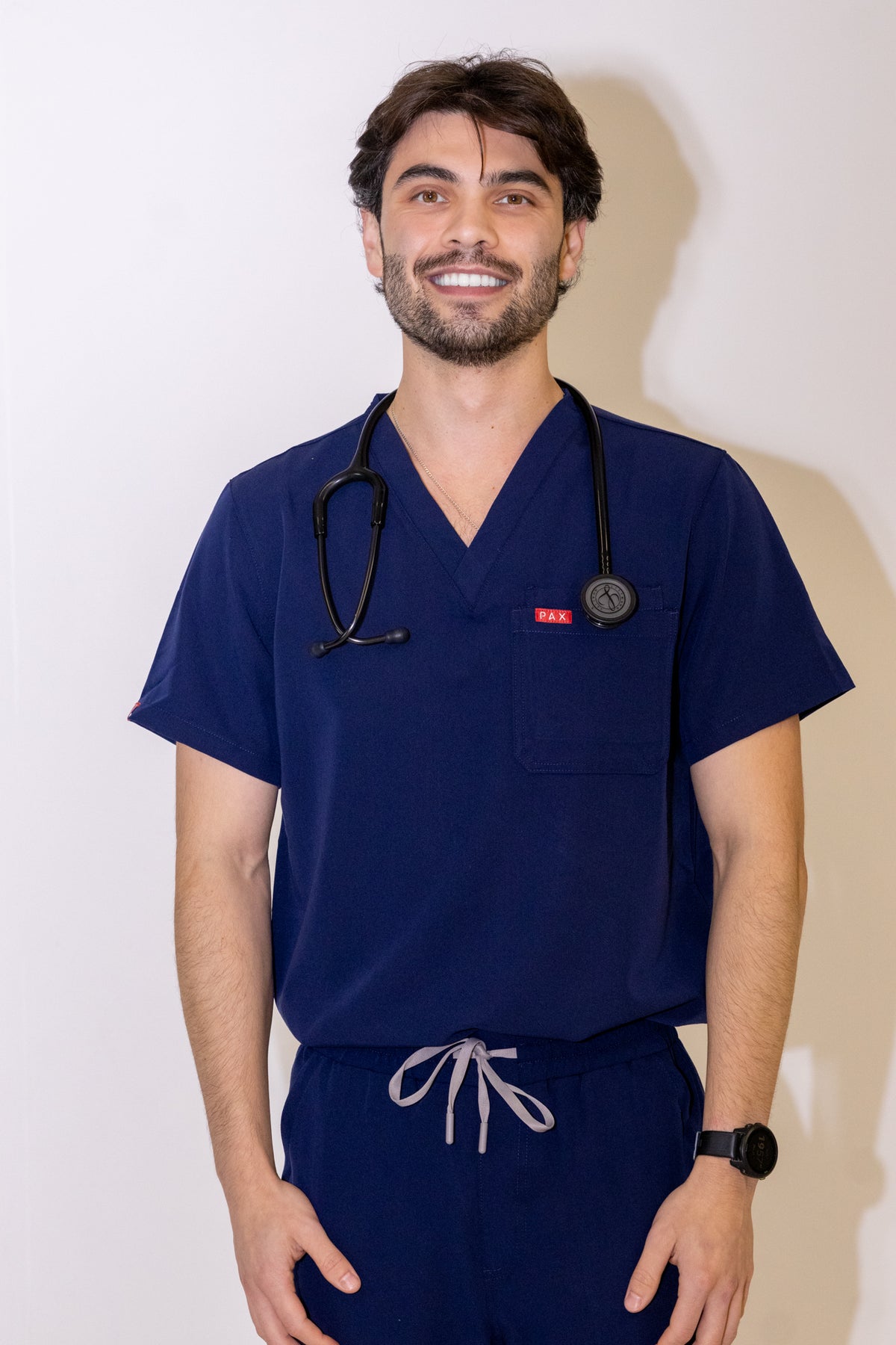 PAX Core Sequi men's navy straight-leg scrub set, front view of the top with a stethoscope