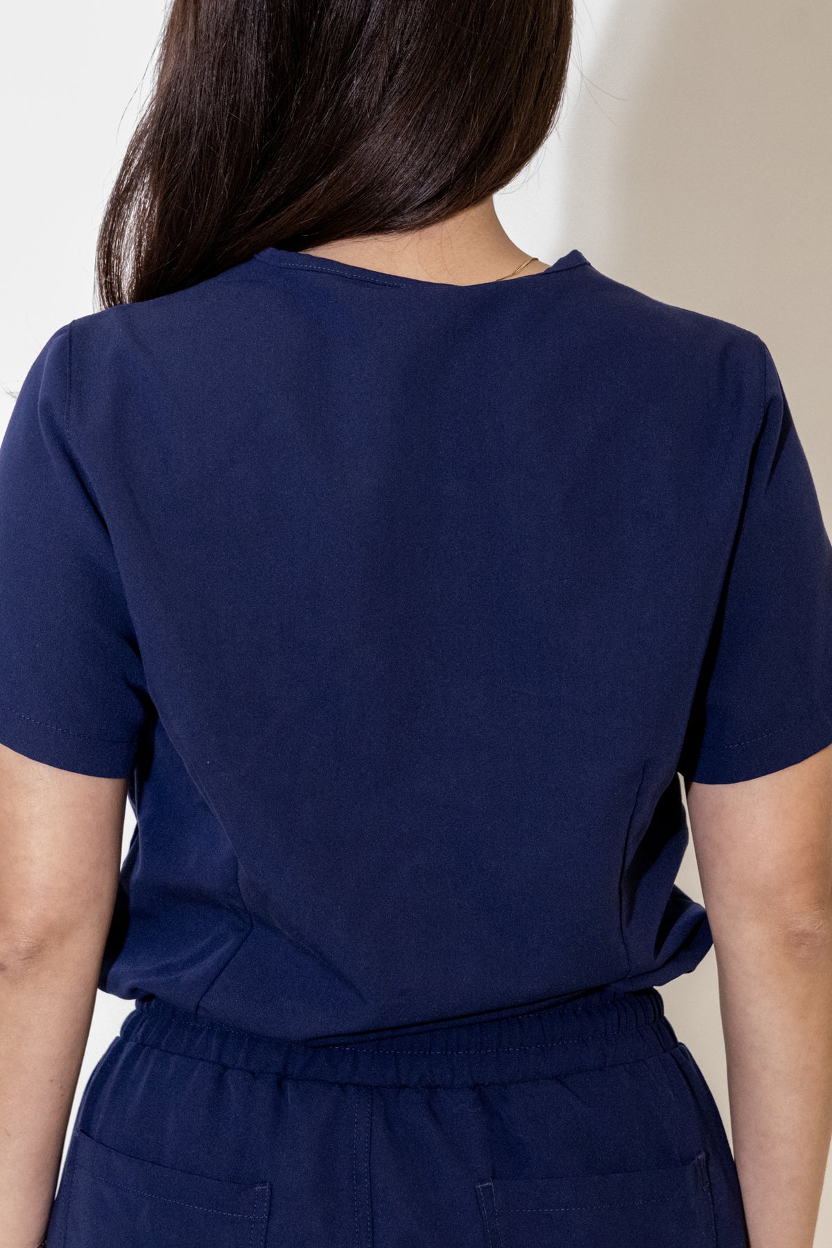 PAX Core Luma women's navy scrub top, back view on a model