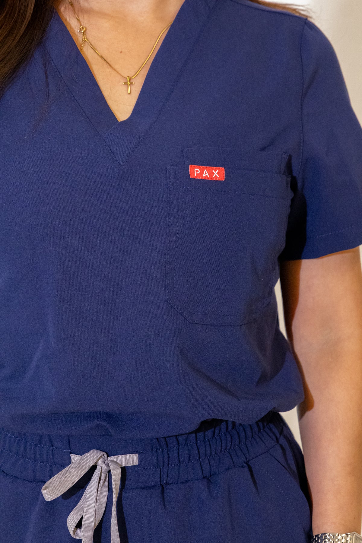 PAX Core Luma women's navy scrub top, V-neck, chest pocket and waistband detail