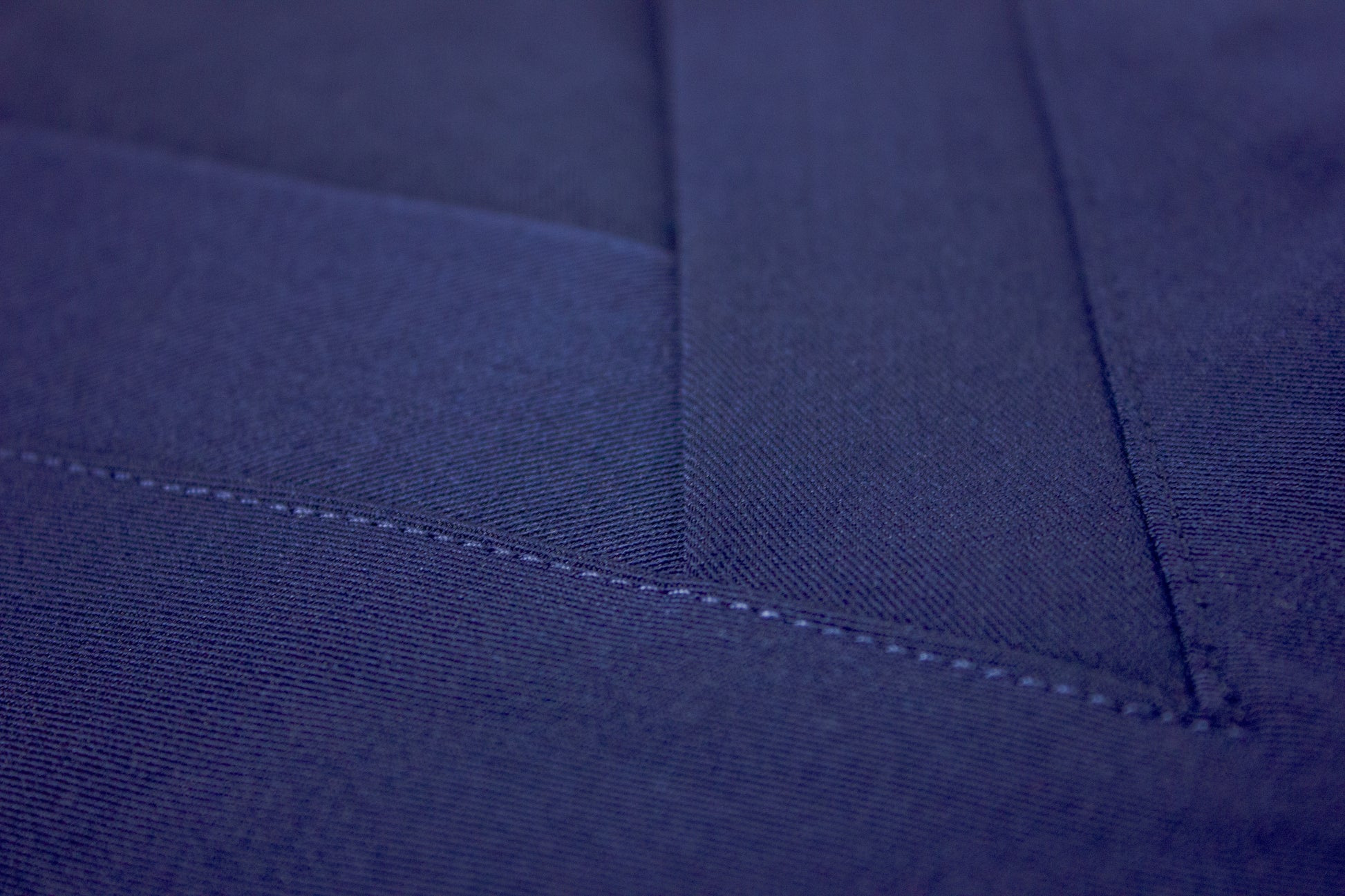 Close-up of stitch detailing on the V-neck of a royal blue scrub top.