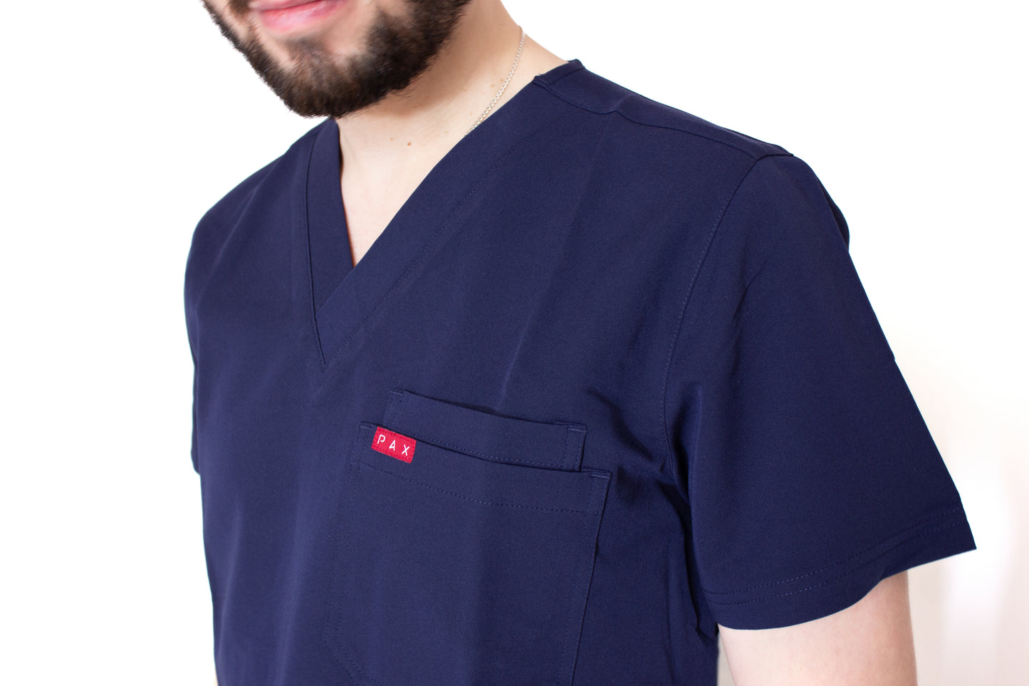Close up of Male scrub top double breast pocket with carmine PAX branding 