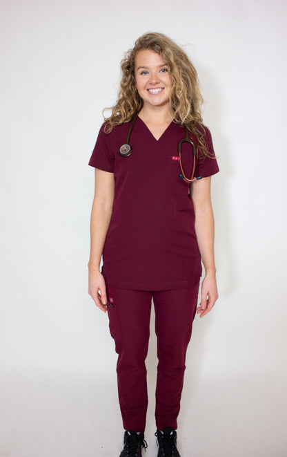 Blonde female doctor modeling a crimson red Primus PAX scrubs set.