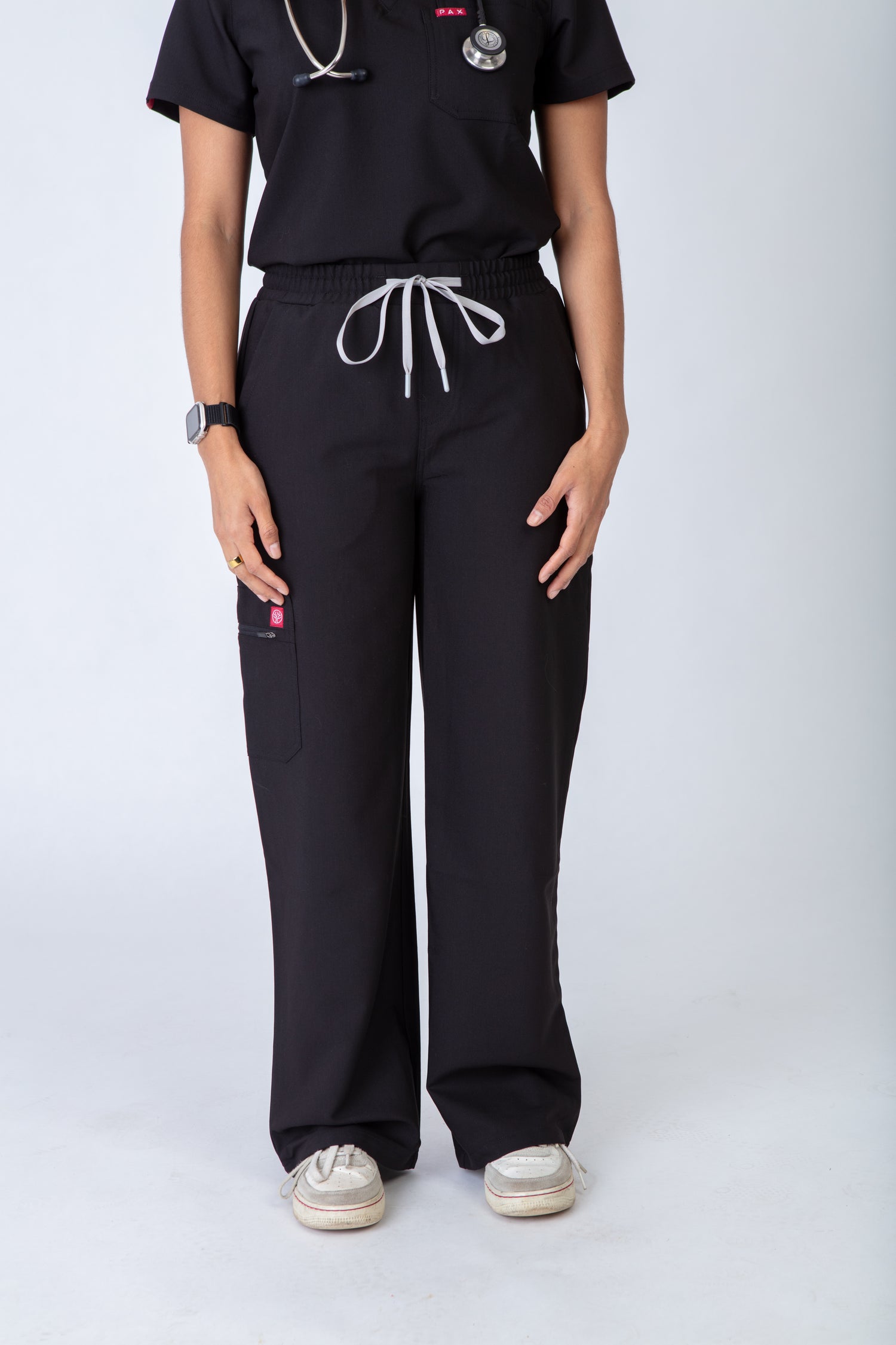 Person wearing black scrubs with white drawstrings on a white background