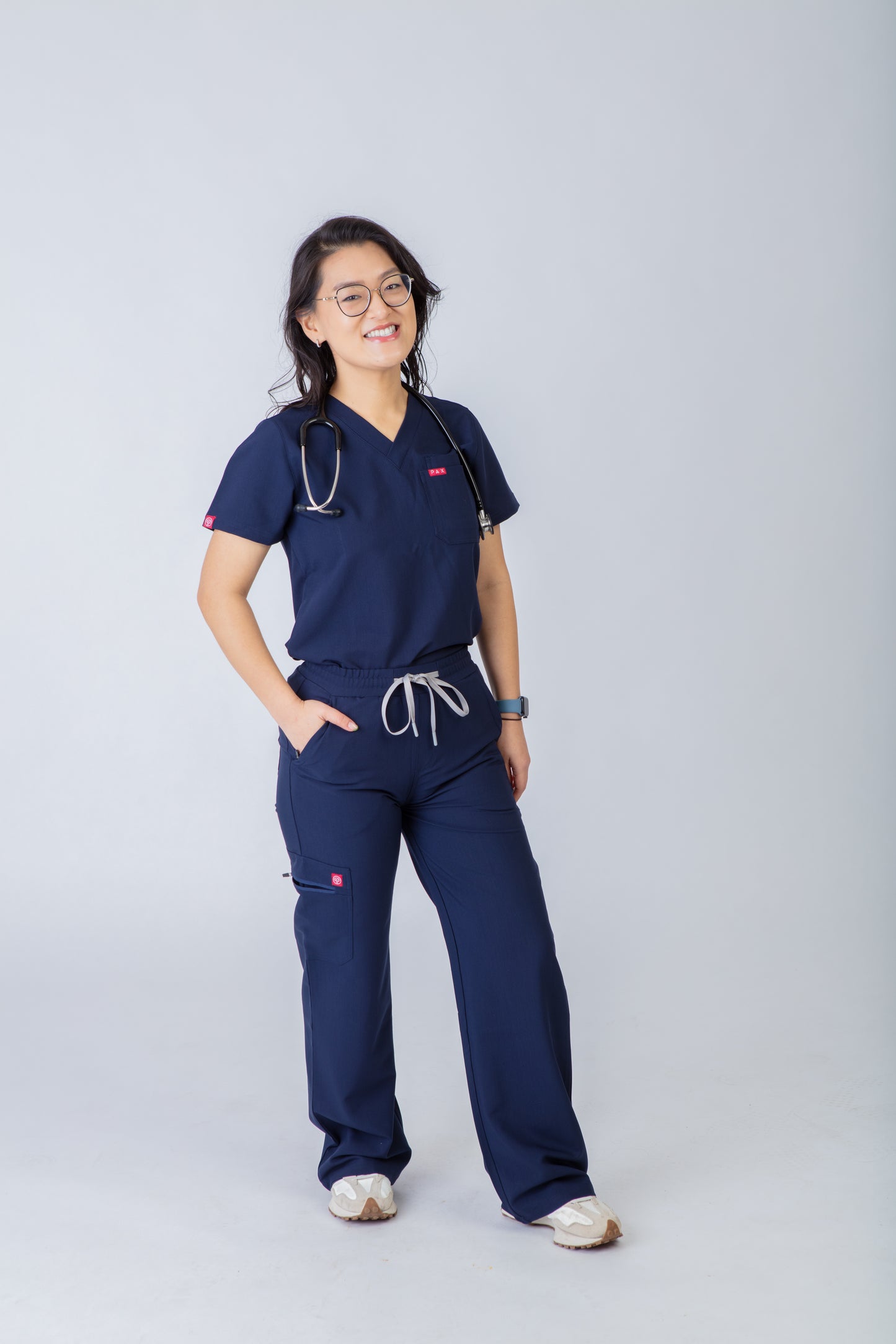 Person wearing navy blue medical scrubs on a gray background