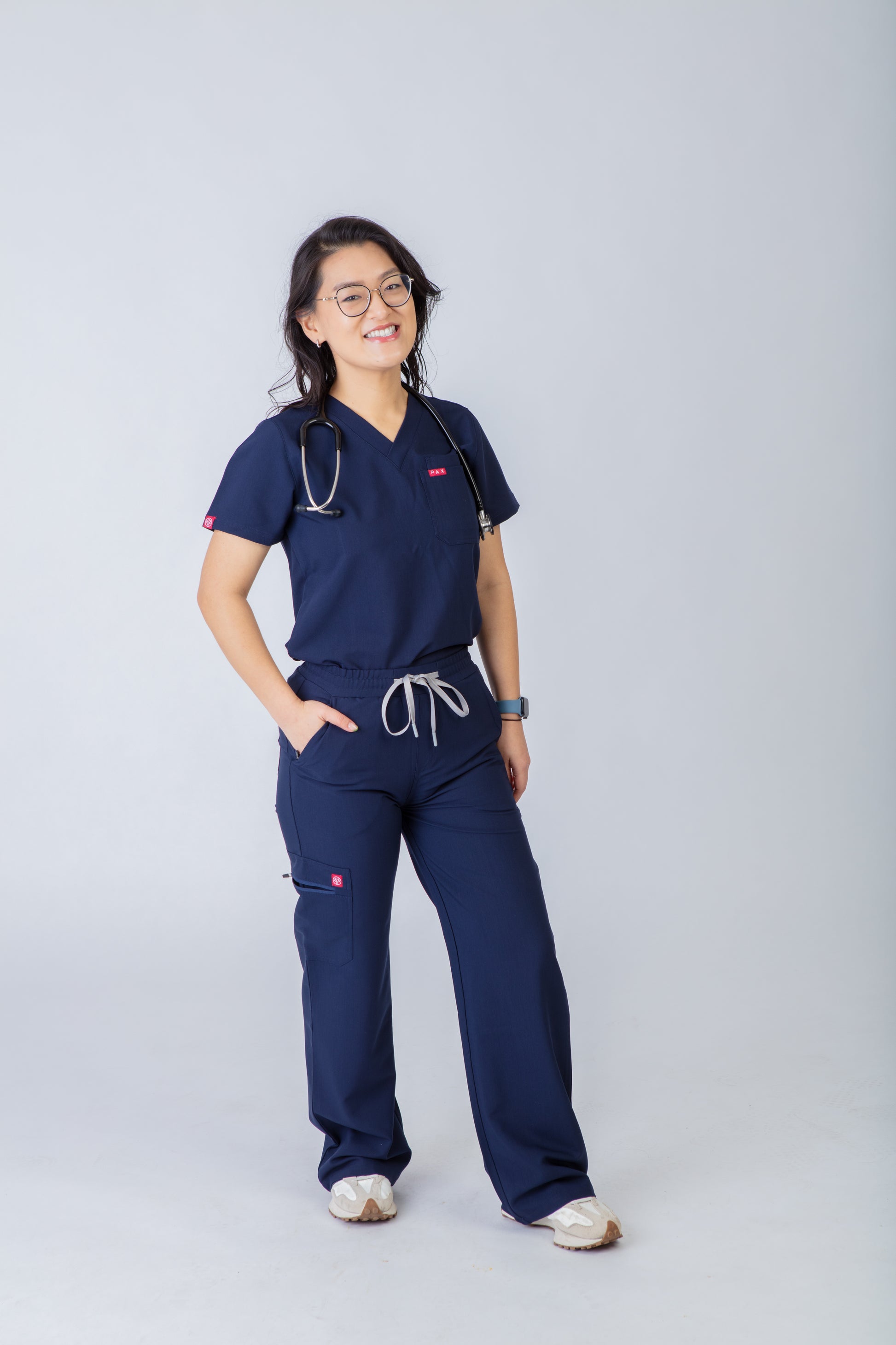 Person wearing navy blue medical scrubs on a gray background