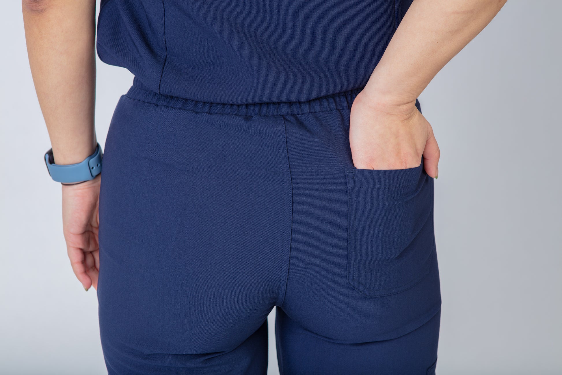 Navy blue scrubs with a rear pocket on a plain background