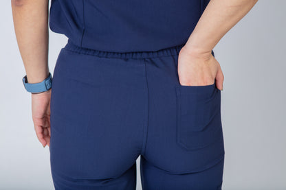 Navy blue scrubs with a rear pocket on a plain background