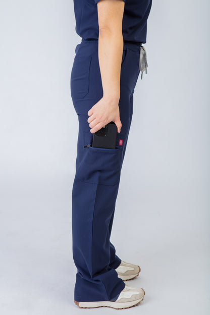 Person wearing navy blue scrubs pants with a pocket on a light gray background