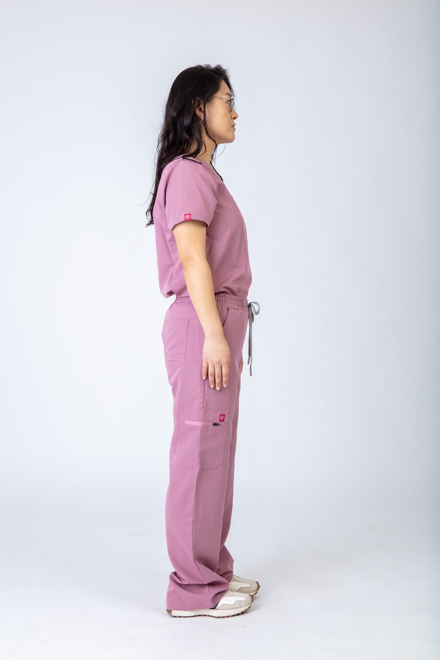 Person wearing a pink scrub set on a white background