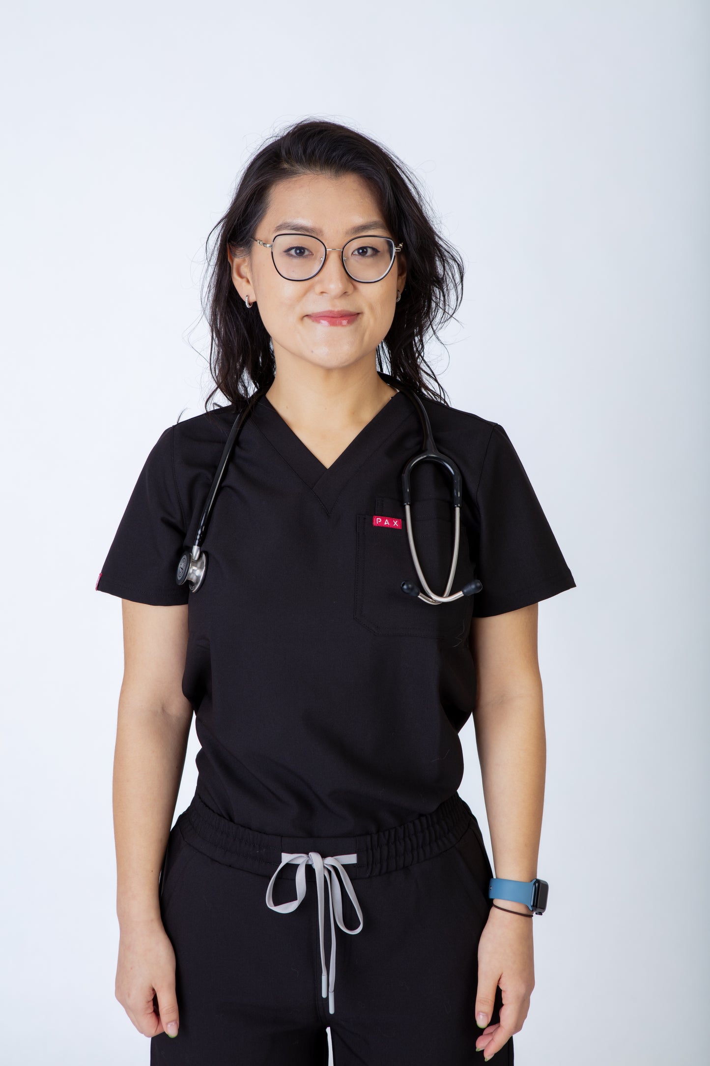 Person wearing black medical scrubs with a stethoscope on a white background