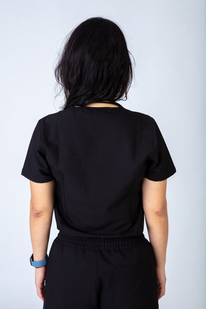 Person wearing a black scrub top against a plain background