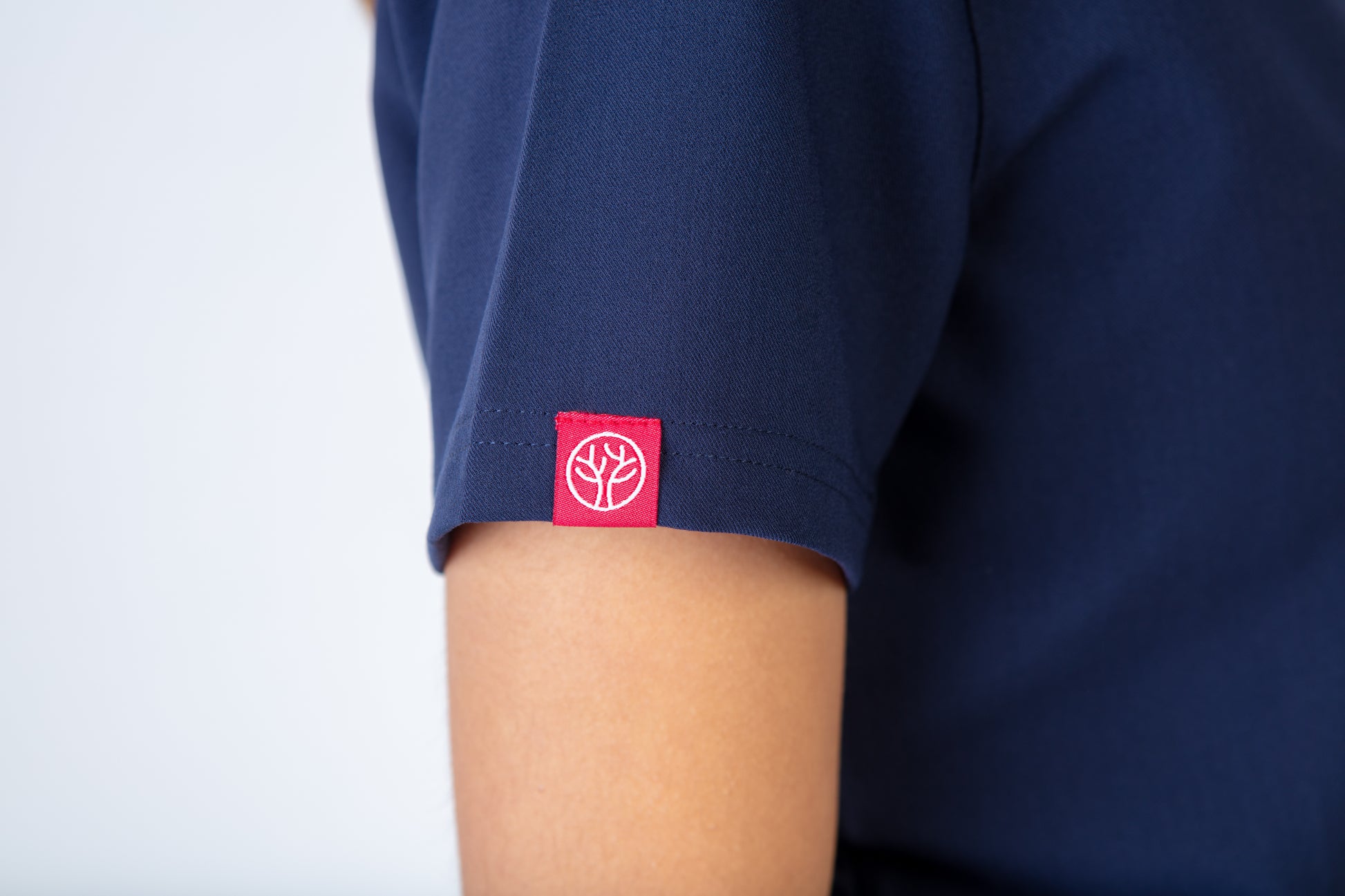 Navy blue shirt with a red logo on the sleeve against a white background