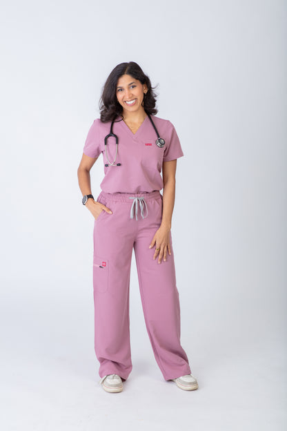 Person wearing pink medical scrubs with a stethoscope on a white background
