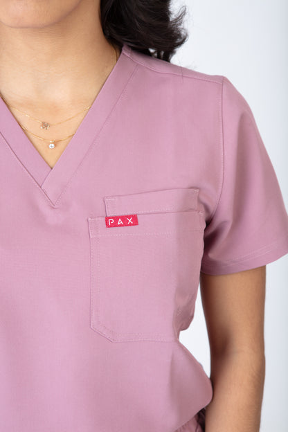 Pink scrub top with a visible brand logo on a white background