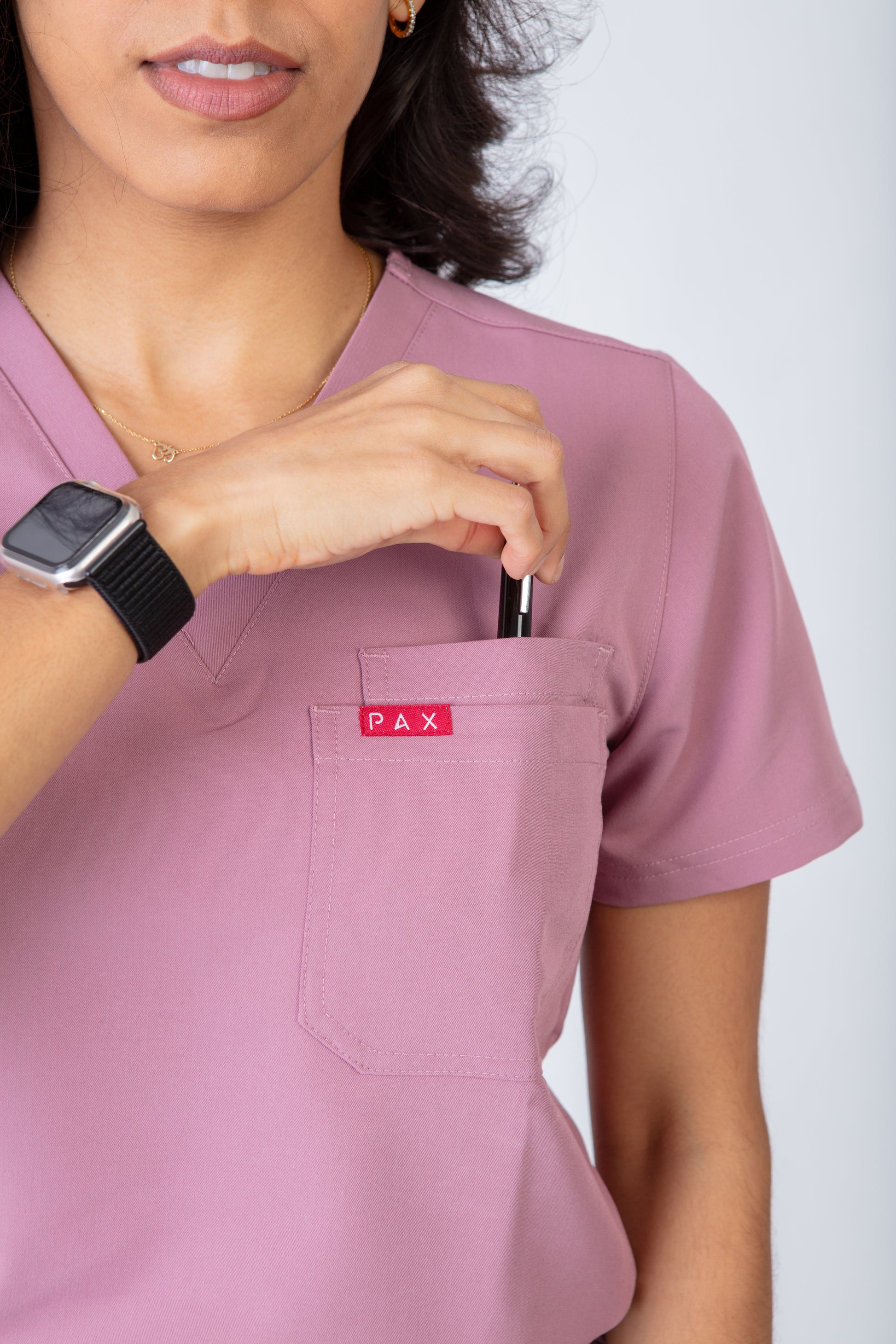 Person wearing a pink scrub top with a 'PAX' logo on a white background